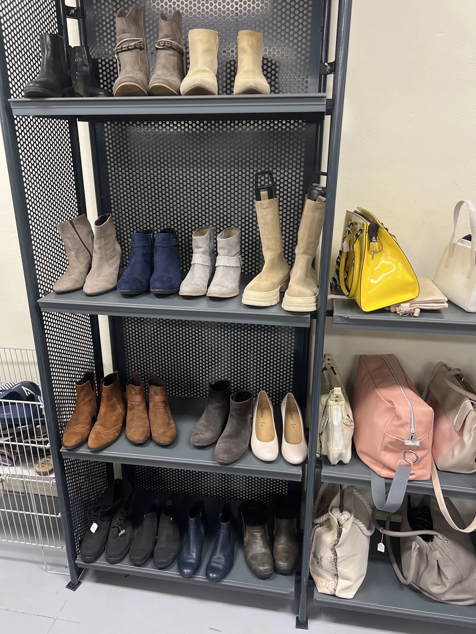 Metalen stellingkast met diverse tweedehands schoenen en laarzen in verschillende kleuren en stijlen