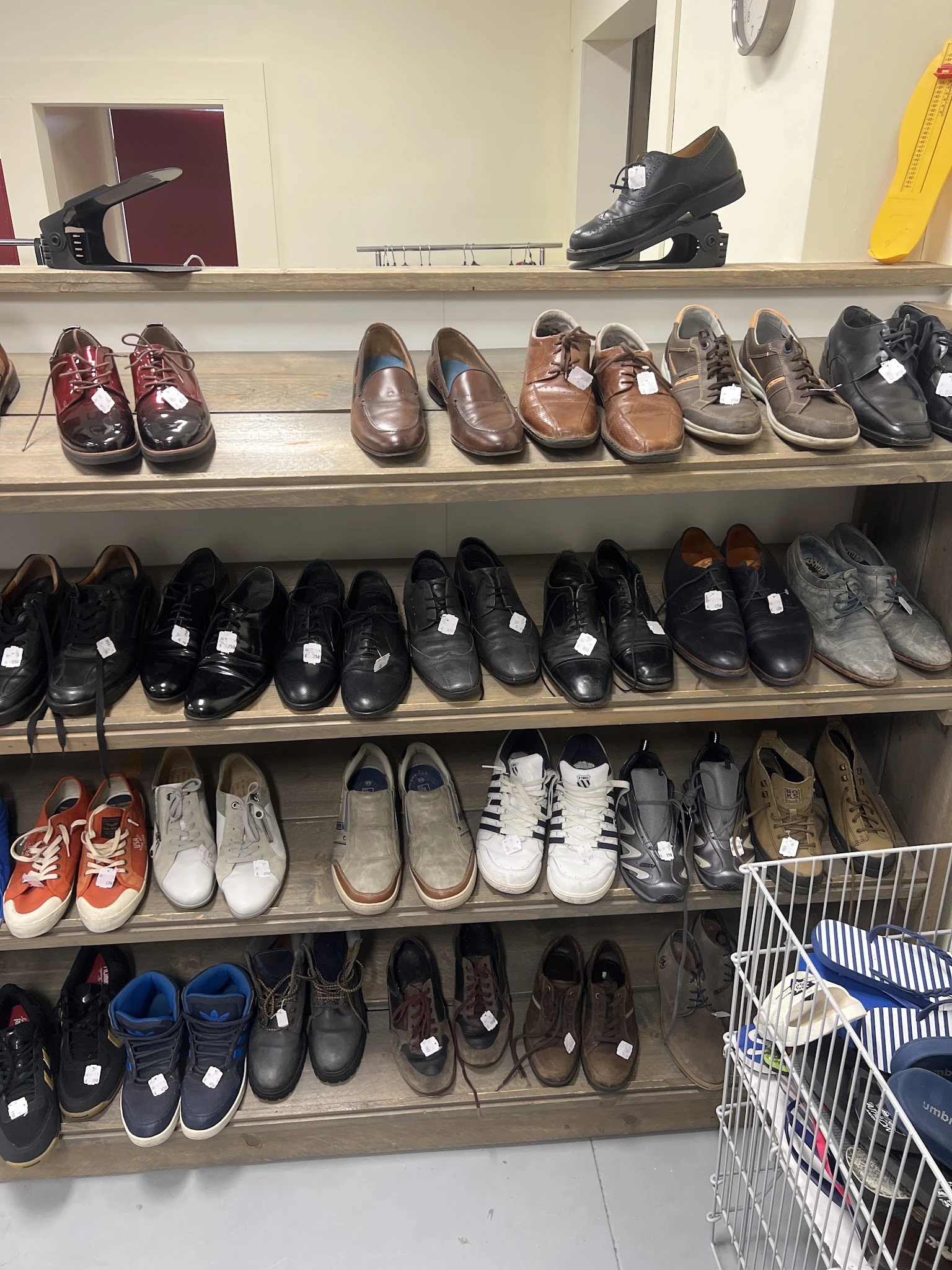 Vier schappen vol met verschillende tweedehands schoenen in diverse kleuren en stijlen