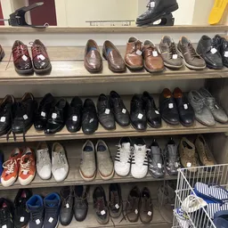 Vier schappen vol met verschillende tweedehands schoenen in diverse kleuren en stijlen