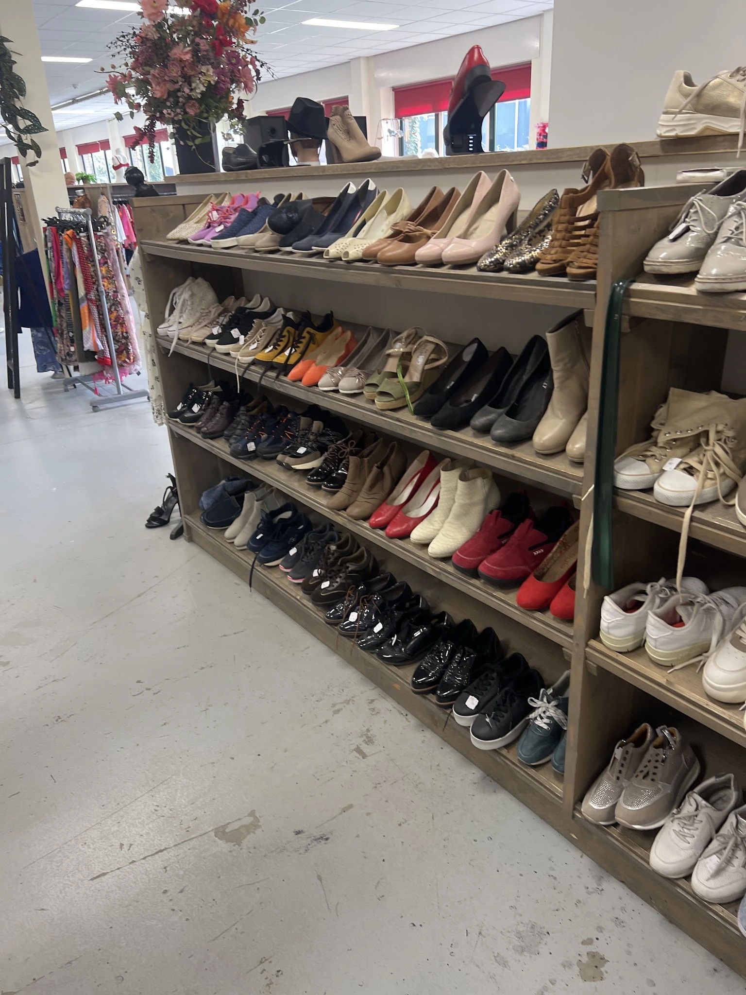 Houten schoenenkast met meerdere planken vol diverse gebruikte schoenen en sneakers