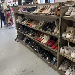 Houten schoenenkast met meerdere planken vol diverse gebruikte schoenen en sneakers