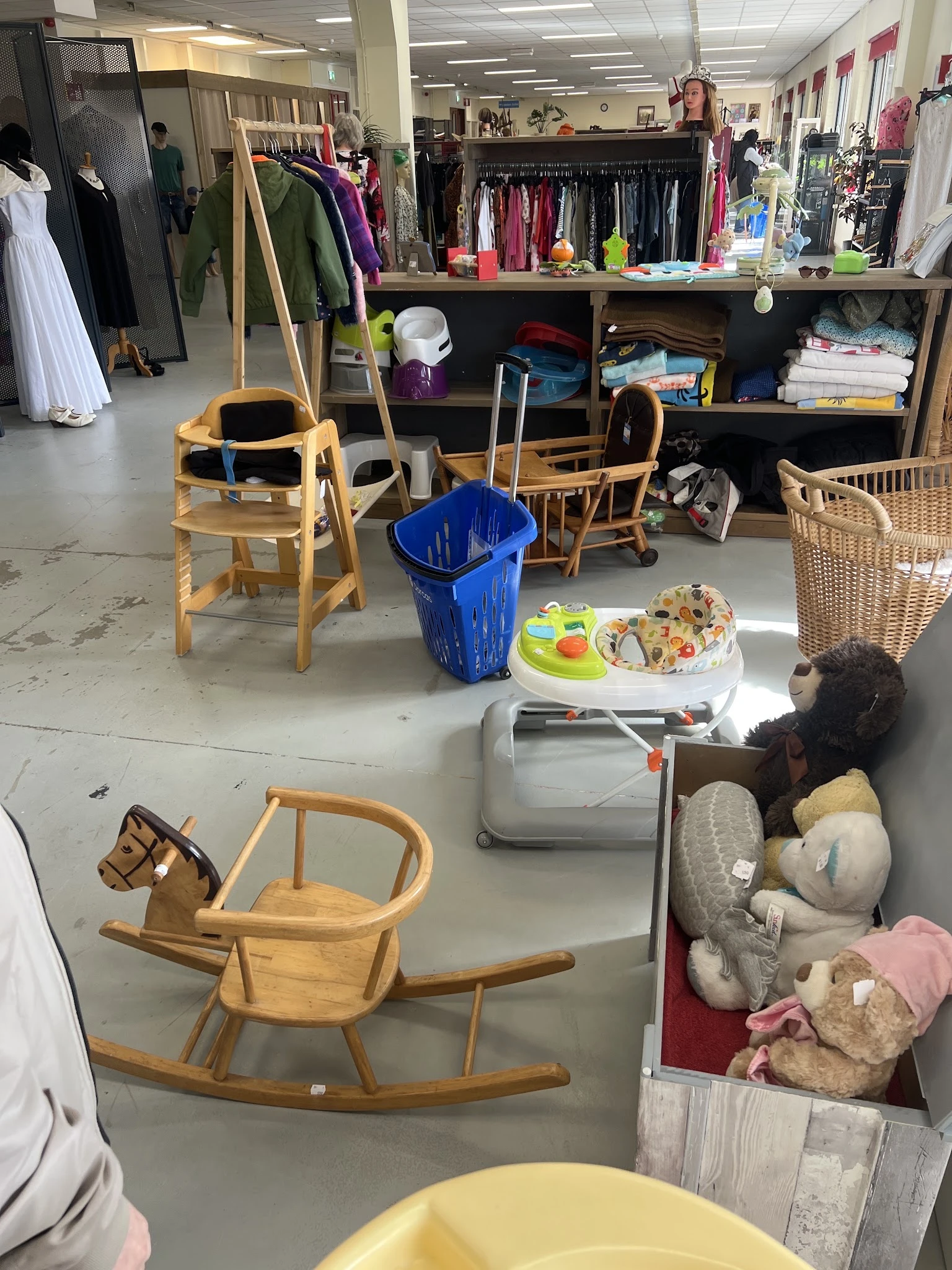 Winkelvloer met houten stoelen, blauwe afvalbak, serviesgoed en dozen met diverse spullen