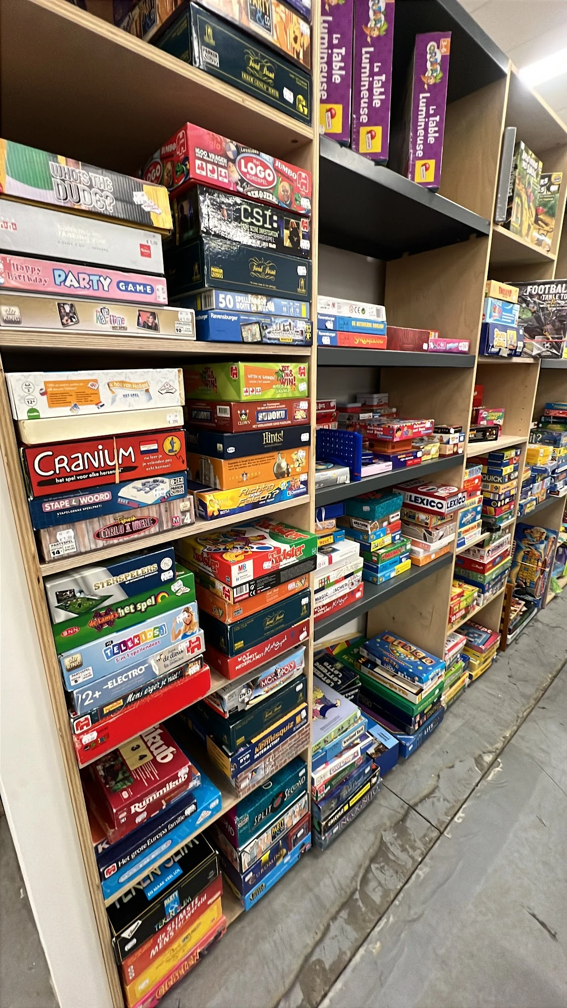 Boekenkasten vol met gestapelde bordspellen en spelletjes in dozen