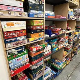Boekenkasten vol met gestapelde bordspellen en spelletjes in dozen