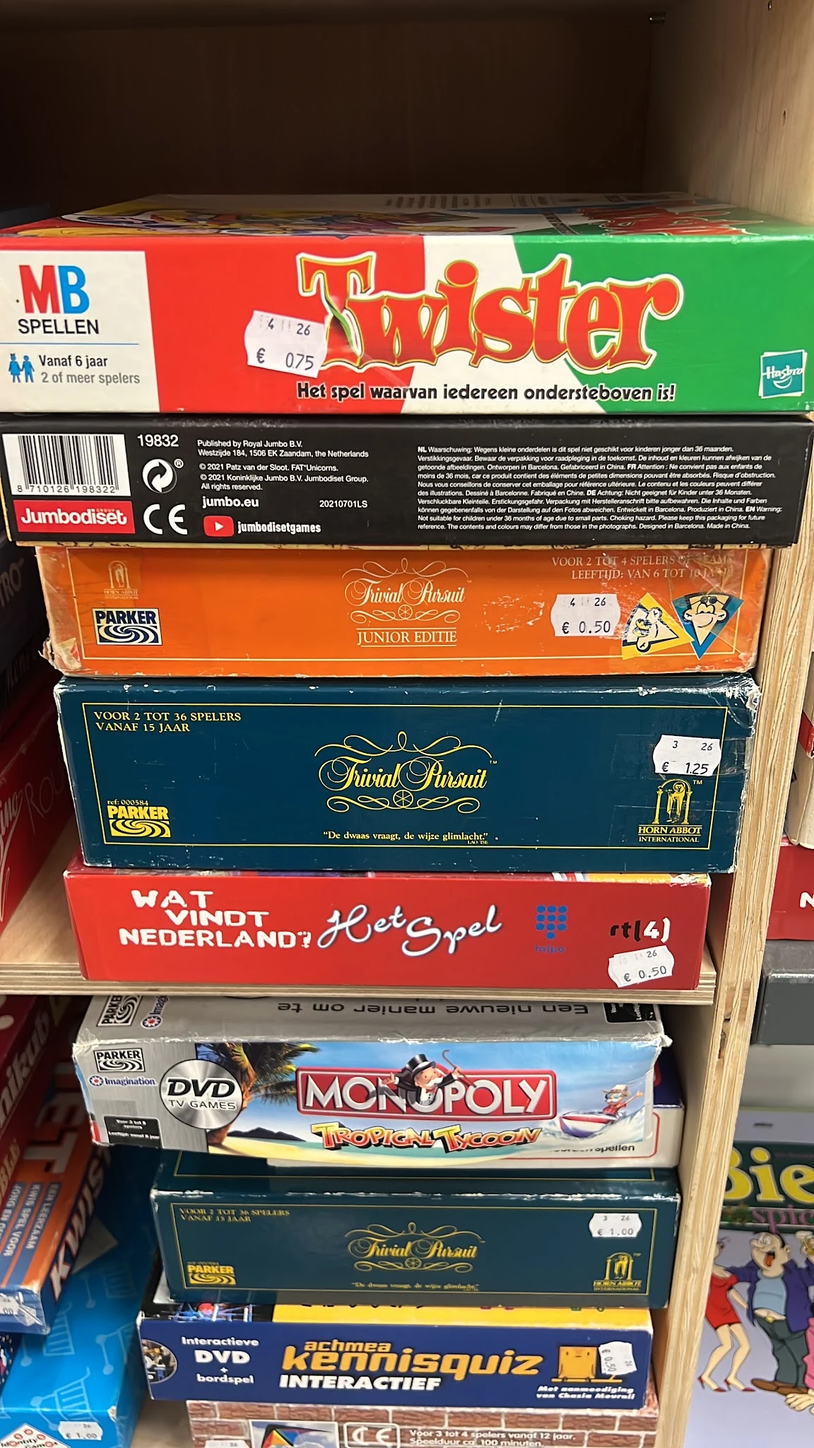 Stapel vintage bordspellen in dozen, waaronder Trivial Pursuit edities en 'Wat Vindt Nederland'-spel