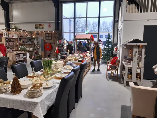 Winkelvloer met uitgeklede tafels, kerstdecoraties en zithoeken in een grote ruimte met grote ramen
