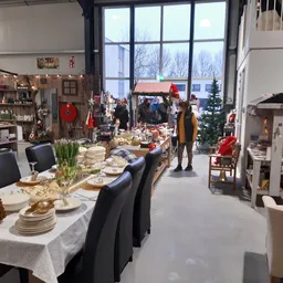 Winkelvloer met uitgeklede tafels, kerstdecoraties en zithoeken in een grote ruimte met grote ramen