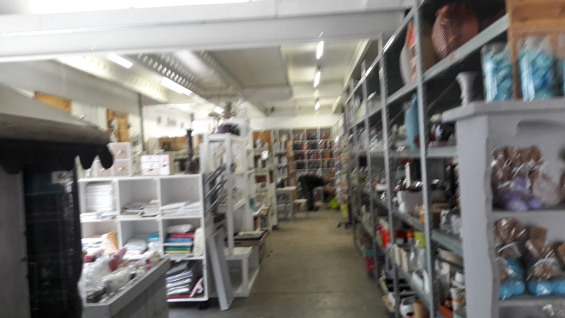Winkelinterieur met stellingen vol boeken en voorwerpen aan beide zijden van een gang