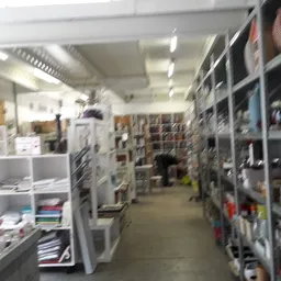 Winkelinterieur met stellingen vol boeken en voorwerpen aan beide zijden van een gang