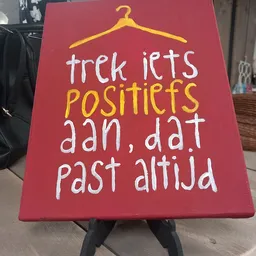 Rood bord met wit en geel handgeschreven tekst met motiverende boodschap
