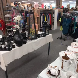 Winkelvloer met kledingrekken, uitgestalde serviesgoed en decoratieve items op tafels