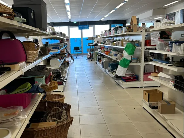 Overzicht van de winkelruimte met stellingen langs beide zijden vol spullen en dozen op de grond