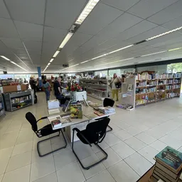 Overzicht van de winkelvloer met boekenkasten, tafels met stoelen en bezoekers tussen de stellingen