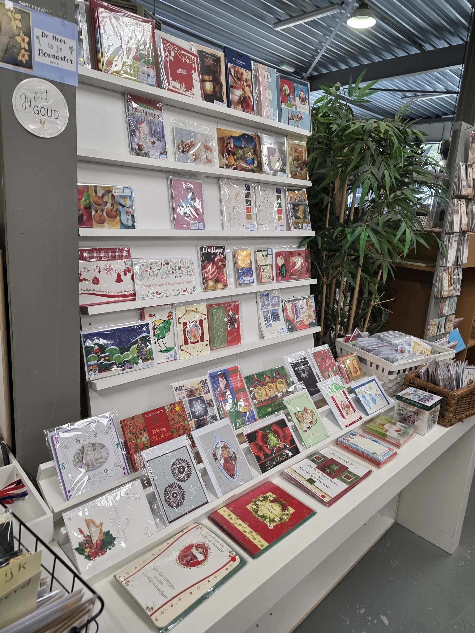 Uitstalling van kerstkaarten en seizoenswaar op planken en toonbank in kringloopwinkel