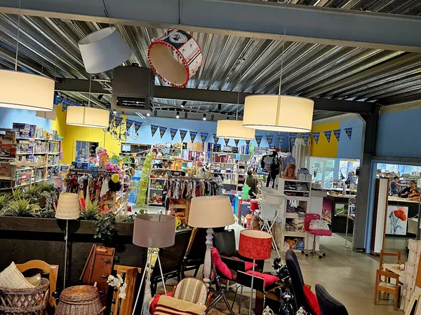 Winkelvloer met stellingen, kleding, meubels en lampen; gele muren en bunting-versiering