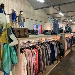 Winkelinterieur met kledingrekken, mannequins met kleding en tassen op houten displaytafels