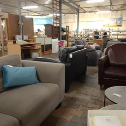 Winkelvloer met diverse fauteuils en zitmeubels uitgestald, kasten en rekken op de achtergrond