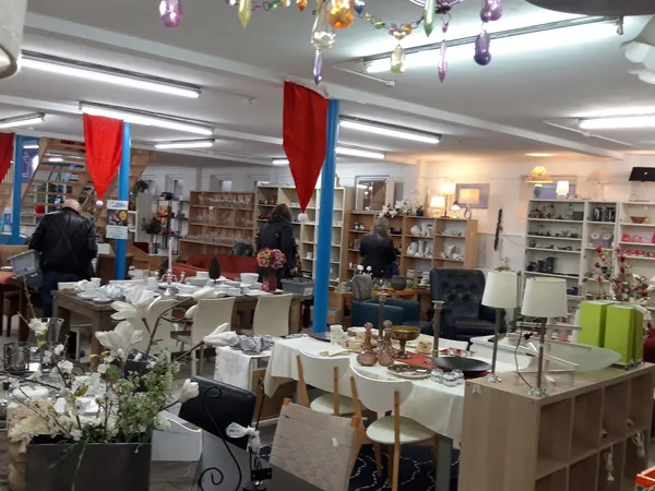 Binnenaanzicht van kringloopwinkel met tafels, stellingen, decoraties en diverse tweedehands spullen