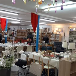 Winkelvloer van kringloopwinkel met tafels, stellingen met spullen, decoraties en verlichting