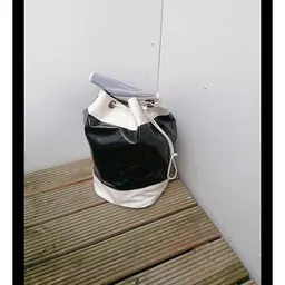 Zwart-wit rugzak of tas op houten vloer tegen grijze muur