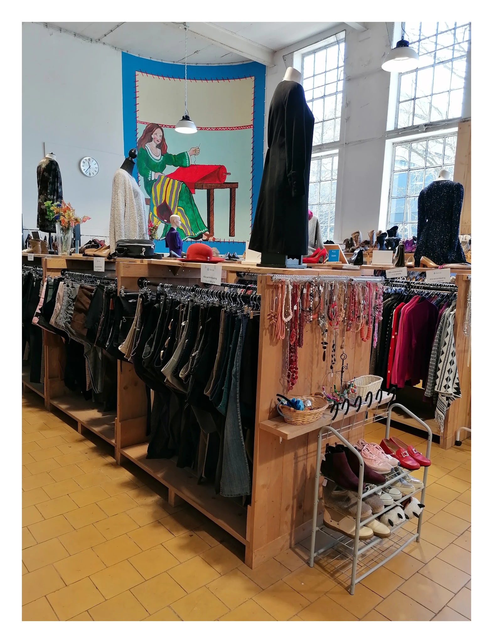 Houten stellingen met uitgestalde tweedehands kleding, schoen en accessoires in de winkel