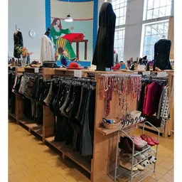 Houten stellingen met uitgestalde tweedehands kleding, schoen en accessoires in de winkel
