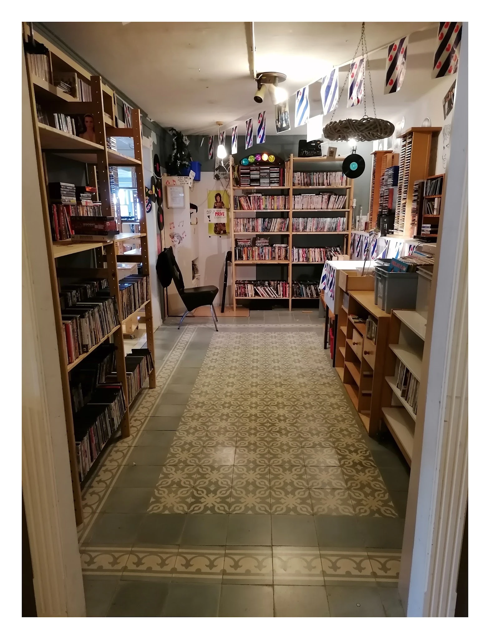 Kringloopwinkel-interieur met boekenrekken langs beide zijden en een leeshoek met stoel in het midden
