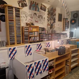Winkelvloer met cd- en platenrekken, houten kasten en wanddecoratie met posters en foto's