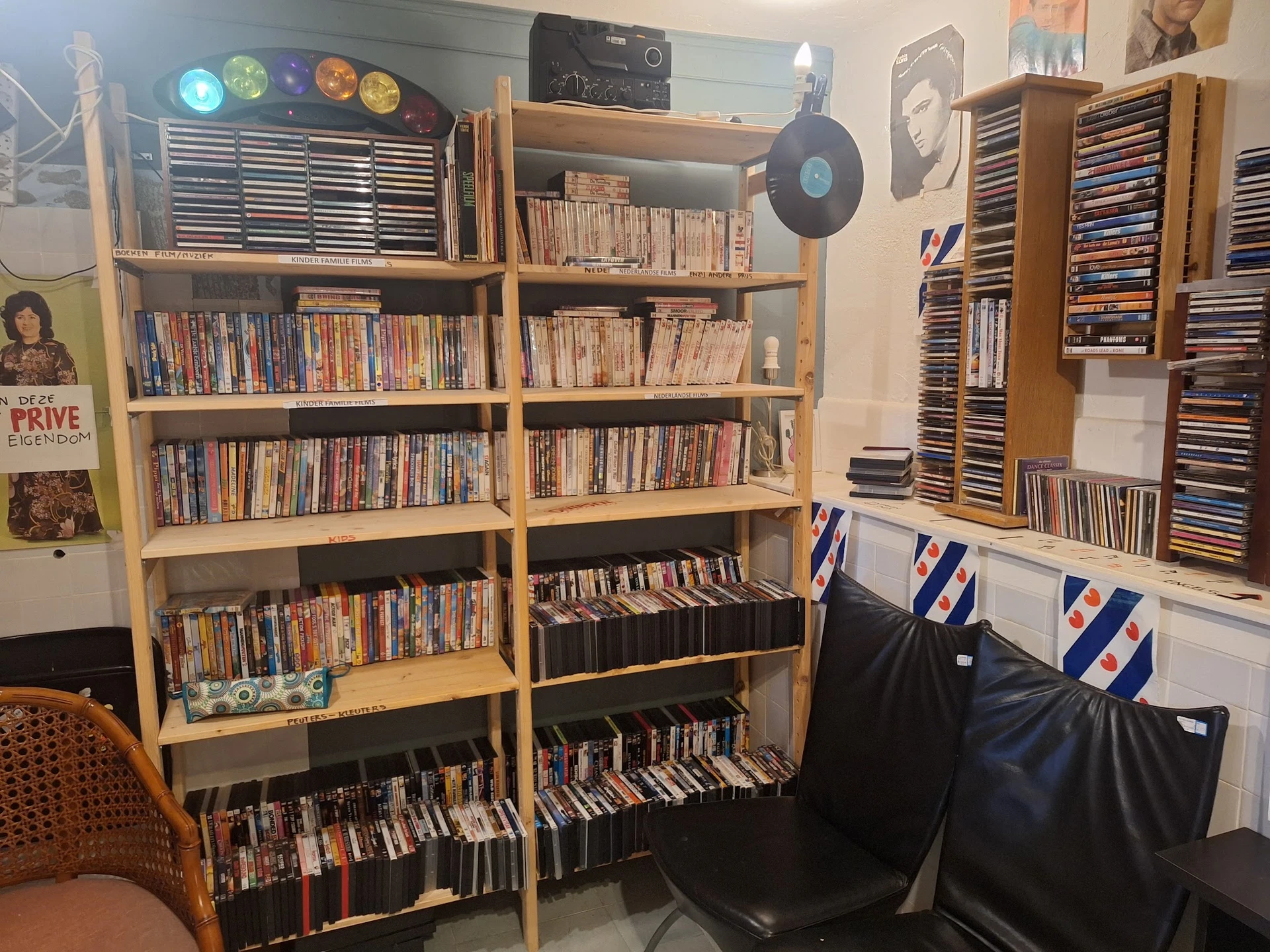 Houten stellingen met grote collectie dvd's en cd's, zwarte opbergkisten eronder