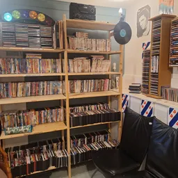 Houten stellingen met grote collectie dvd's en cd's, zwarte opbergkisten eronder