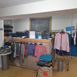Rekken met tweedehands kinderkleding, waaronder jurken en jasjes in verschillende kleuren en maten