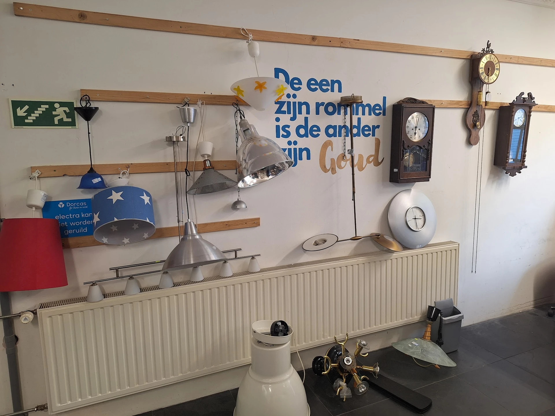 Wandrek met diverse tweedehands huishoudelijke artikelen: lampen, klokken, serviesgoed en decoratie