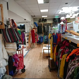 Overzicht van de winkelvloer met rekken vol tweedehands kleding, tassen en diverse artikelen