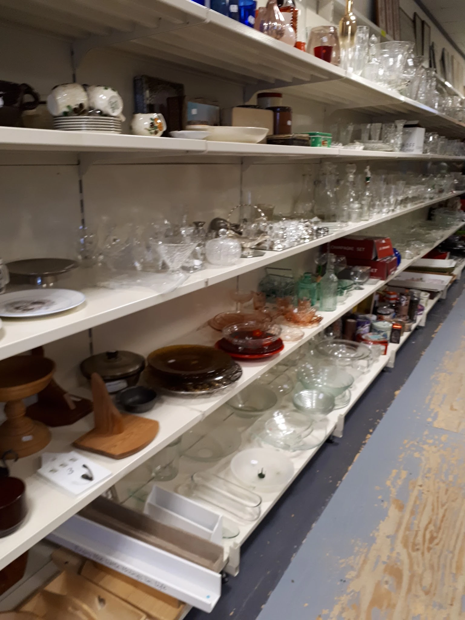 Stellingen met servies, glazen en huishoudartikelen in de kringloopwinkel
