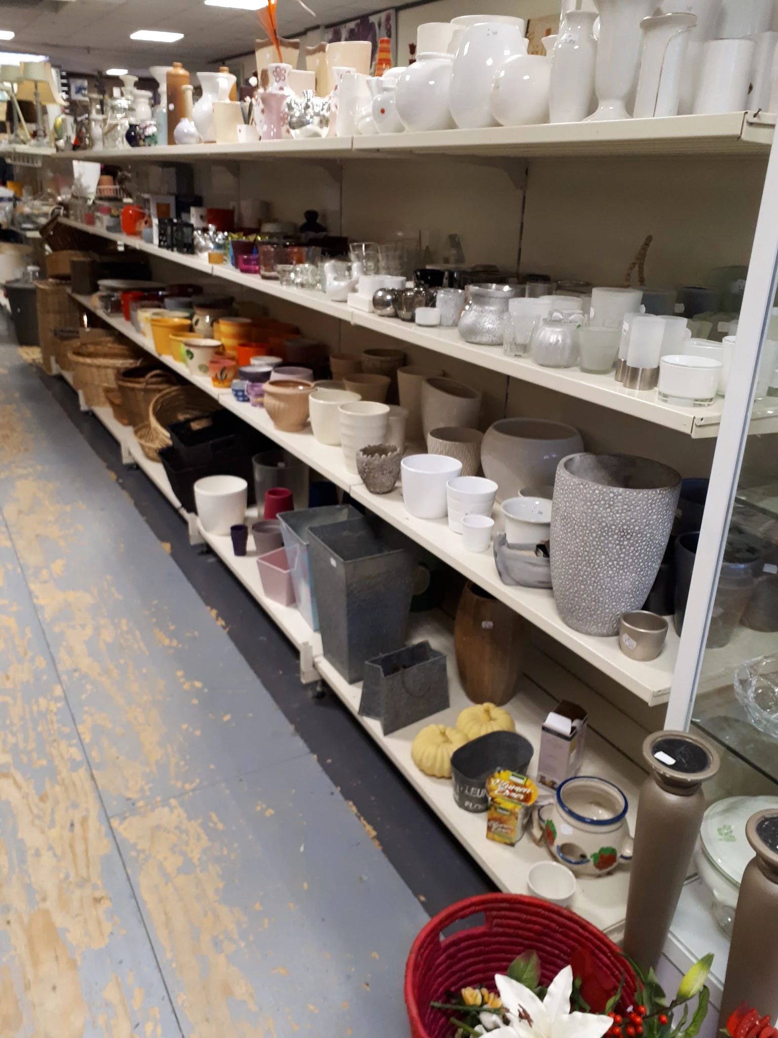 Stellingen met huishoudwaar: potten, bakjes, serviesgoed en decoratieve items