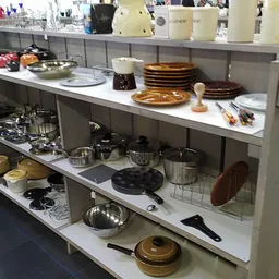 Uitgestalde huishoudelijke artikelen en servies op schappen in de kringloopwinkel, waaronder borden, pannen en keukenspullen