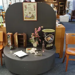 Winkelinterieur met ronde grijze display, houten stoelen en decoratieve artikelen zoals bloemen en vazen