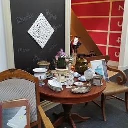 Ingerichte woonkamer met ronde tafel, servies en decoraties in kringloopwinkel