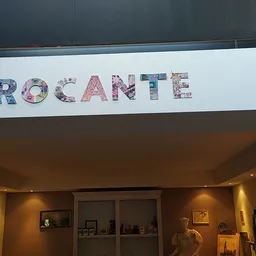 Decoratief bord met het woord 'BROCANTE' in bloemmotief letters aan winkelmuur