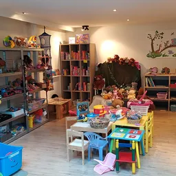 Kinderkamer in kringloopwinkel met speelgoed, boeken, meubels en speeltafels op houten vloer