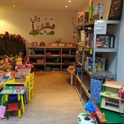 Speelgoedafdeling in kringloopwinkel met kindertafels, speelgoed, boeken en houten meubels