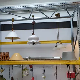 Uitgestalde vintage lampen en hanglampen op gele stellingen in de kringloopwinkel