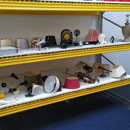 Gele stellingkasten met diverse huishoudelijke artikelen zoals lampen, servies, pannen en decoratieve voorwerpen