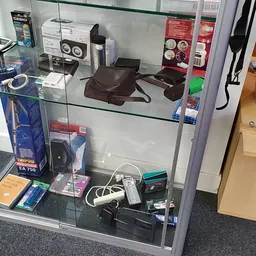 Vitrinekast met tweedehands elektronica: speakers, adapters, kabels en accessoires