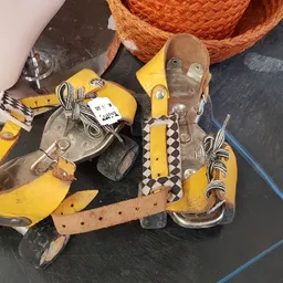 Gele rolschaatsen met bruine onderdelen op donkere ondergrond
