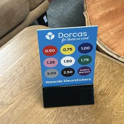 Blauwe displaykaart met Dorcas-logo en gekleurde stickers met prijzen van 0,50 tot 2,50 euro
