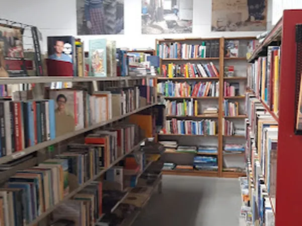 Boekenrekken met tweedehands boeken in diverse genres, langs gangpad in kringloopwinkel