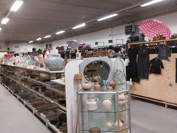 Winkelvloer met toonbanken, stellingen met huishoudelijke artikelen en kleding aan hangers