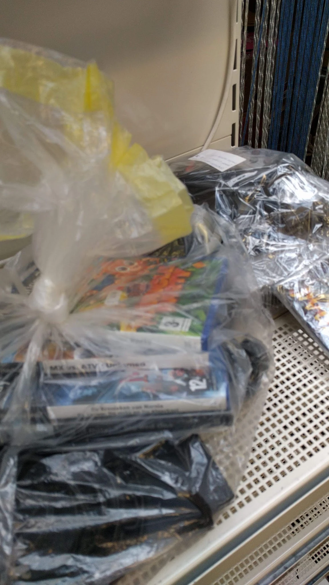 Plastic zakken met tweedehands speelgoed en kinderartikelen op een schap