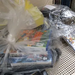 Plastic zakken met tweedehands speelgoed en kinderartikelen op een schap